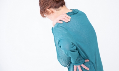慢性的な肩こり腰痛を抱える女性